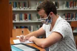 young man in library wearing mask