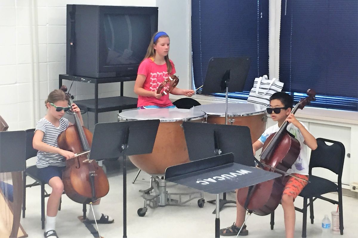 Three students pay cellos and rhythm instruments
