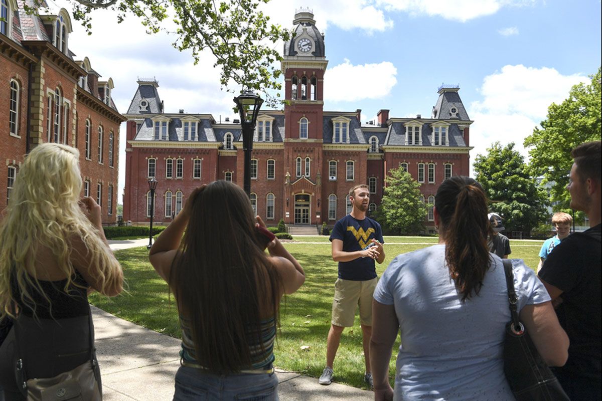 young man talks to group in front of WVU's Woodburn Hall