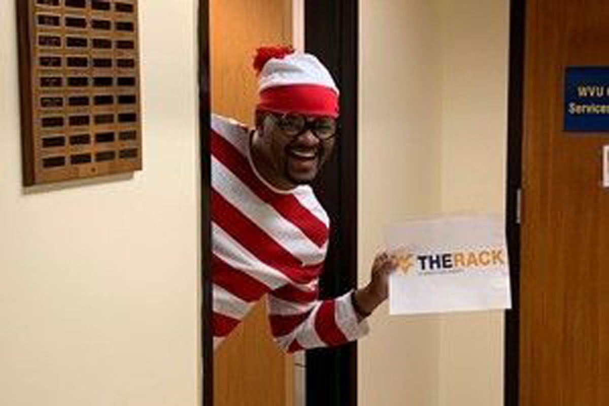 A student dressed up as Where's Waldo holding a sign that reads, 