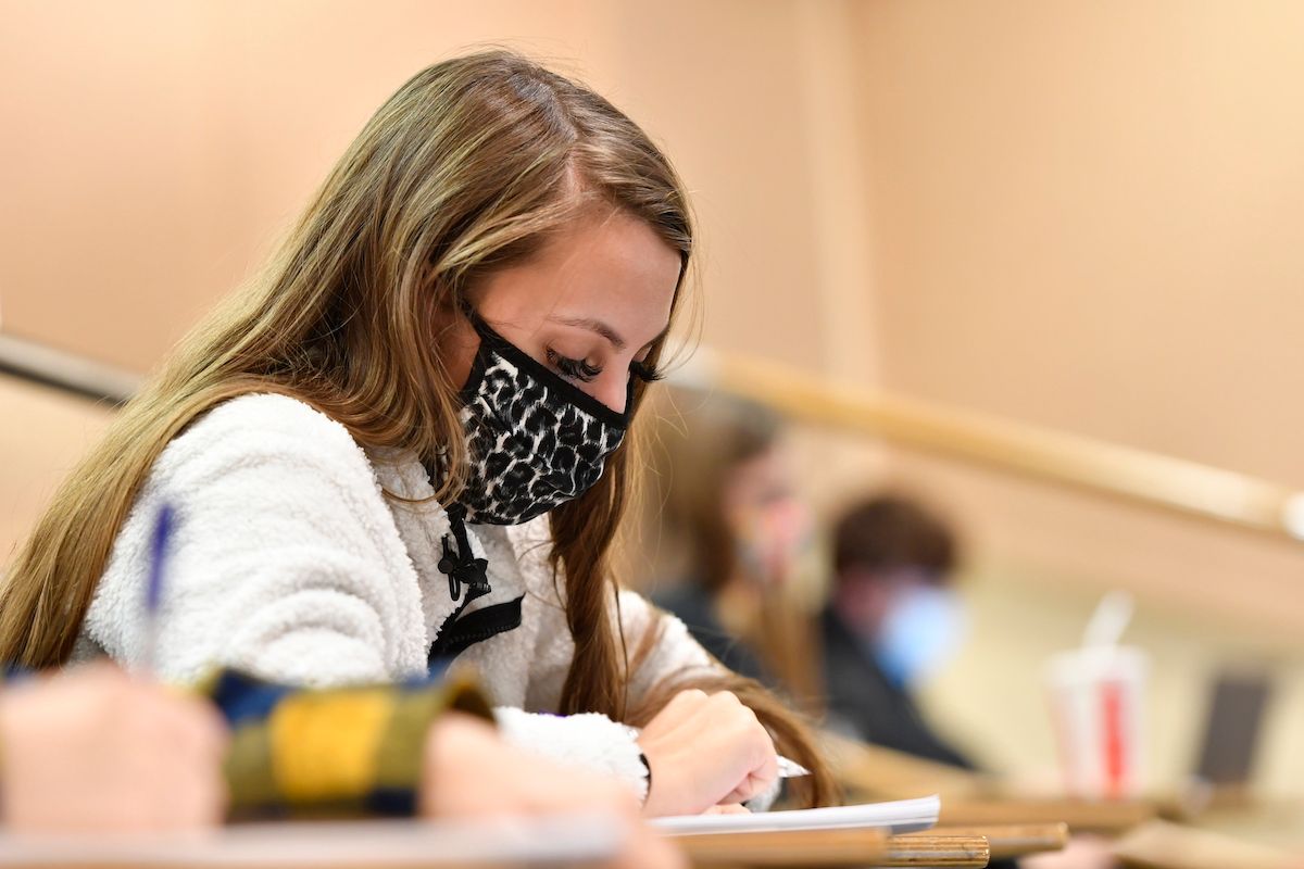woman wearing mask taking notes