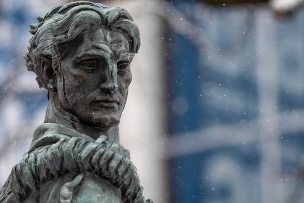 This is a headshot of the Mountaineer statue on the left side of the frame. The Mountainlair is visible in the background and there is light snow falling.
