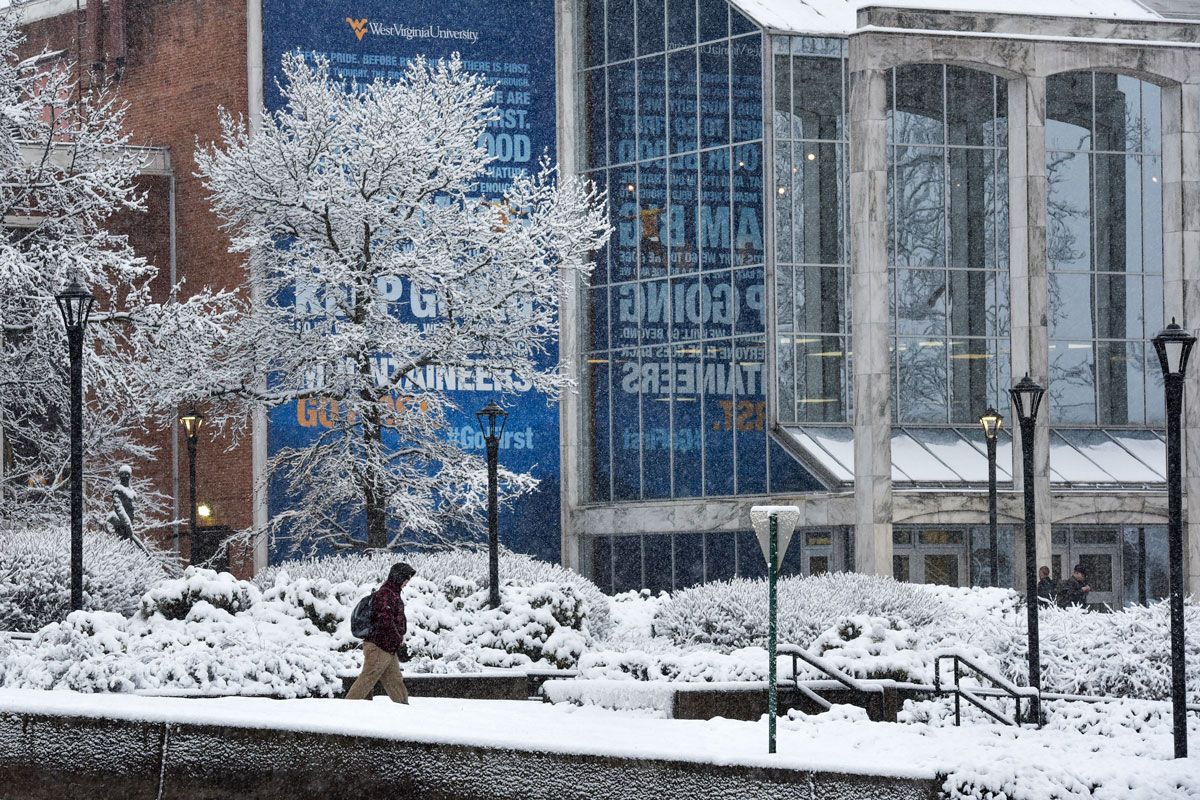 A student walking through an empty, snow covered campus.
