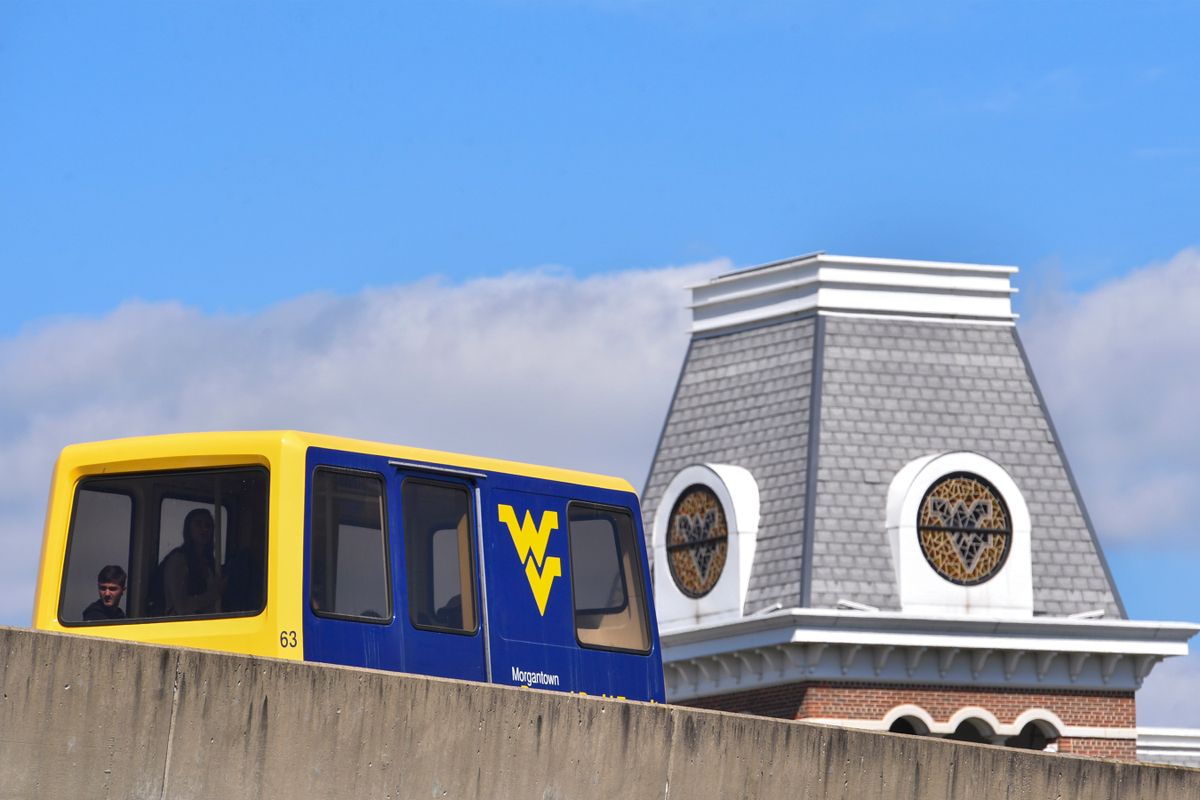 A PRT on the tracks with a WVU building in the background.
