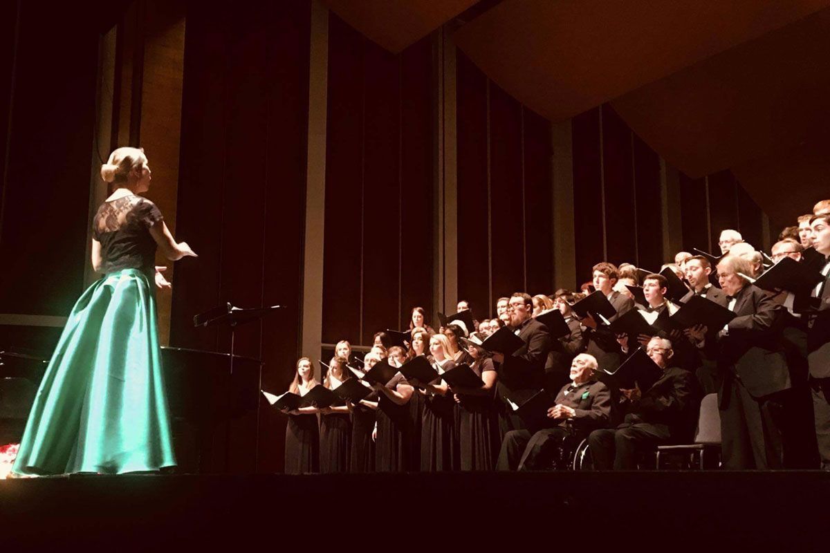A woman in a dress conducting an orchestra.
