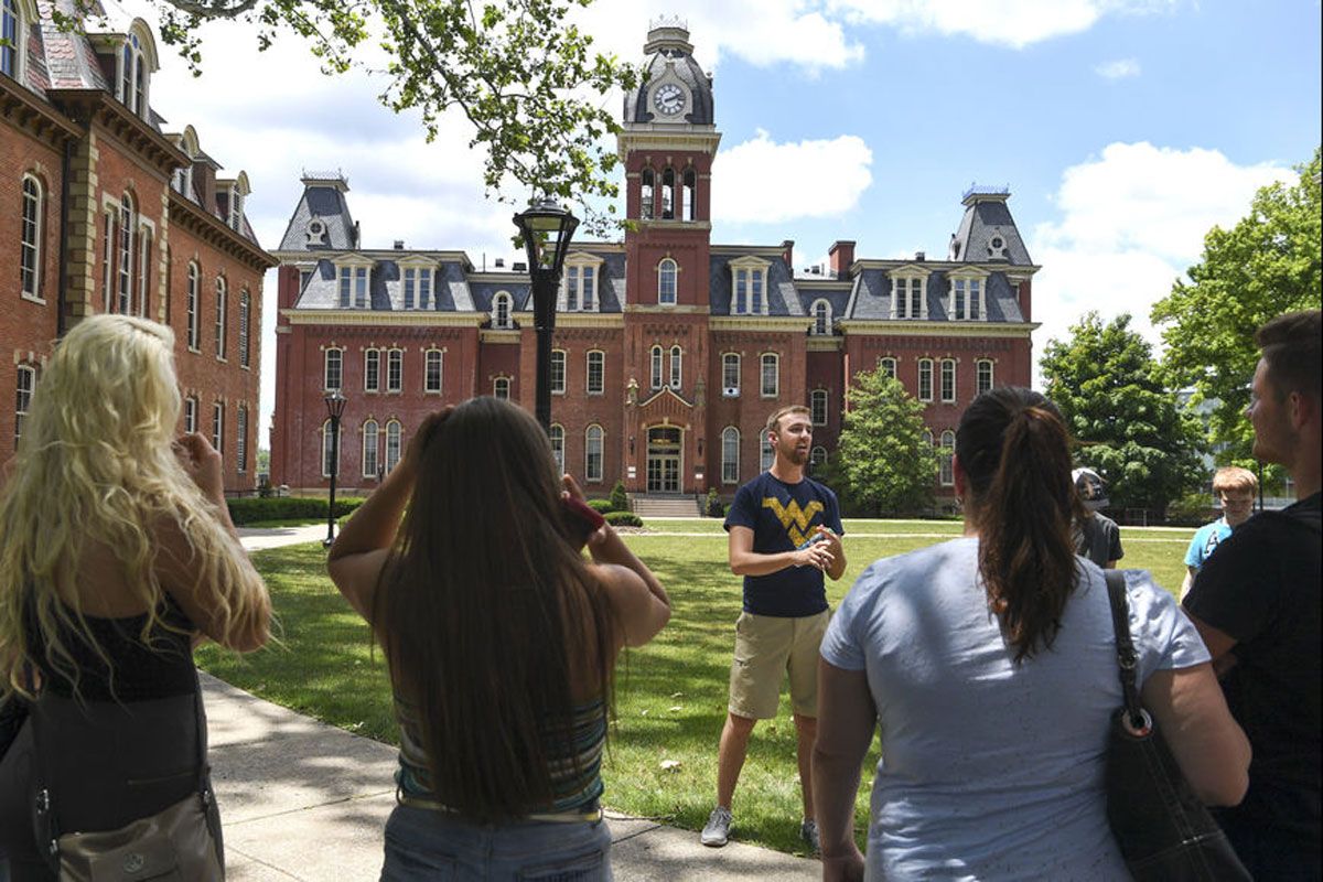 a man talks to people in front of WVU's Woodburn Hall