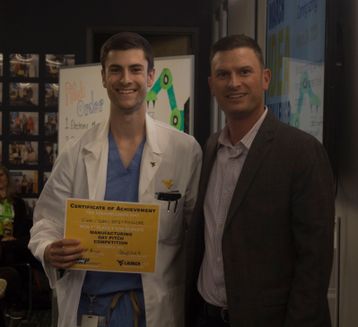 man in white coat stands next to another man holding a certificate