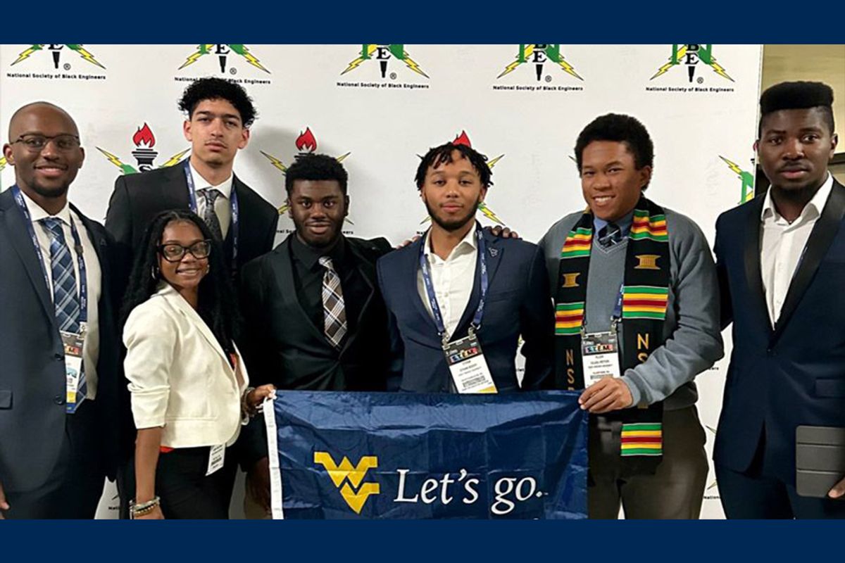 Members of the WVU chapter of National Black Engineers hold a Let's Go flag with a Flying WV.