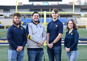 Four students standing on Mountaineer football field.